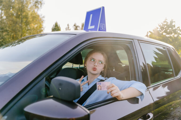 girl sitting in car after successfully passing her driving test using the steps to getting her driver's license